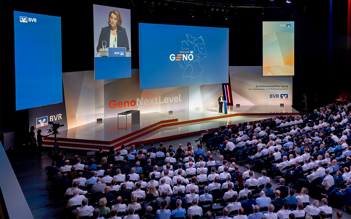 „Wir müssen unsere Erträge steigern“, betonte BVR-Präsidentin Marija Kolak in ihrer Eröffnungsrede zur 80. Bankwirtschaftlichen Tagung im Juli 2025 in Berlin. Dabei gelte es, sich mit vielen Konkurrenten auseinanderzusetzen, die oft schneller, aggressiver und globaler agieren. „Wir dürfen nicht tatenlos zusehen und den Tech-Giganten einfach den digitalen Raum überlassen“, unterstrich Kolak. Und: „Lassen Sie uns als Gruppe das nächste Level gemeinsam erreichen.“